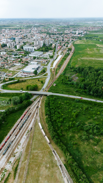Aerial view of freight trains on railway tracks near a road bridge and urban buildings in Sabac Vojvodina Serbia.