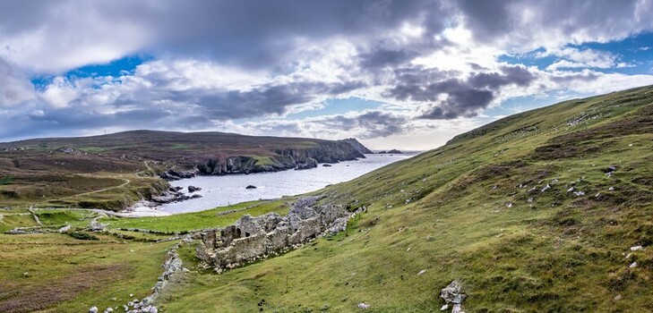 Aerial view of the historic stone ruins at An Port nestled in the rugged green hills overlooking the Atlantic Ocean coastline in Ardara County Donegal Ireland.