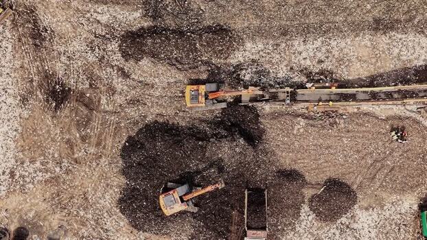 Aerial view of waste recycling site with excavators in India.