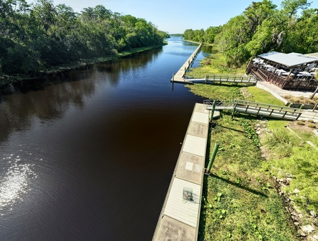 Aerial view of a dark river flowing between lush green banks and wooden docks under a bright sky St. Augustine Florida United States. Aerial view of a dark river flowing between lush green banks and wooden docks under a bright sky St. Augustine Florida United States.