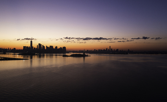 Aerial view of the New York skyline and the Statue of Liberty silhouetted against a vibrant sunrise over the harbor in New York New York United States.