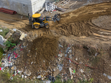 Aerial view of a yellow backhoe loader working on a dirt construction site with piles of earth debris and tire tracks in Istanbul Istanbul Turkiye. Aerial view of a yellow backhoe loader working on a dirt construction site with piles of earth debris and tire tracks in Istanbul Istanbul Turkiye.