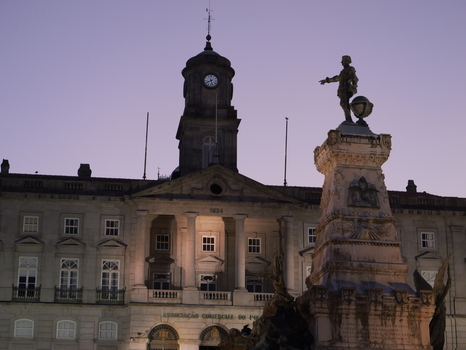View of the Palacio da Bolsa with its neoclassical facade and clock tower featuring a prominent statue in the foreground under a twilight sky in Porto Porto District Portugal. View of the Palacio da Bolsa with its neoclassical facade and clock tower featuring a prominent statue in the foreground under a twilight sky in Porto Porto District Portugal.