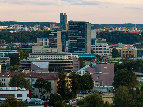 Aerial view of the modern skyline featuring glass skyscrapers and office buildings surrounded by lush green trees in the city of Vilnius Vilnius County Lithuania. Aerial view of the modern skyline featuring glass skyscrapers and office buildings surrounded by lush green trees in the city of Vilnius Vilnius County Lithuania.