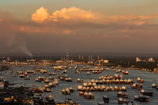 Chittagong Bangladesh 01 September 2021 Aerial view of cargo ships and vessels anchored in the busy port during golden hour with industrial infrastructure in the background.