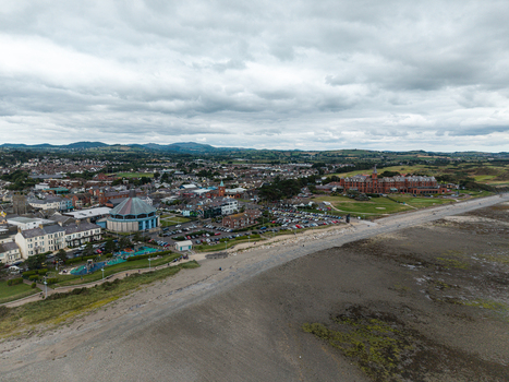 Aerial view of the coastal town of Newcastle with the Slieve Donard hotel sandy beach and surrounding green hills under a cloudy sky in Newcastle Northern Ireland United Kingdom. Aerial view of the coastal town of Newcastle with the Slieve Donard hotel sandy beach and surrounding green hills under a cloudy sky in Newcastle Northern Ireland United Kingdom.