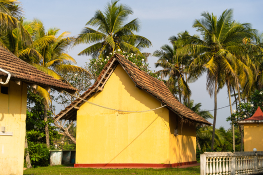 View of a traditional yellow building with a tiled roof surrounded by lush palm trees under a clear sky in Galle Southern Province Sri Lanka.