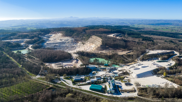 Aerial view of the quarry s stark white terraces contrasting with the surrounding lush greenery a stark juxtaposition of industry and nature &Eacute;chassi&egrave;res Auvergne Rh&ocirc;ne Alpes France.