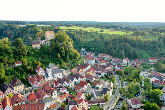 Aerial view of Pottenstein Castle on a rocky hill overlooking the historic town center with its church and traditional red roofed houses Pottenstein Bavaria Germany. Aerial view of Pottenstein Castle on a rocky hill overlooking the historic town center with its church and traditional red roofed houses Pottenstein Bavaria Germany.