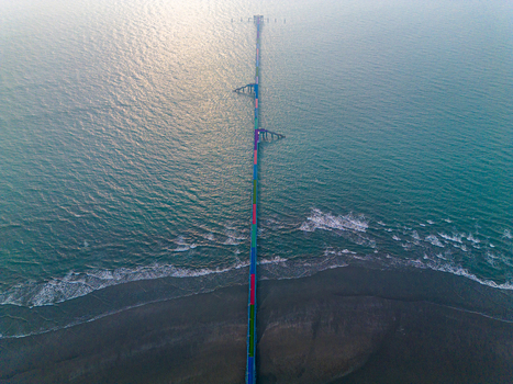 Aerial view of a long pier stretching into the sea its colorful structure a vibrant contrast against the muted tones of the water and shore Cox s Bazar Chittagong Division Bangladesh.