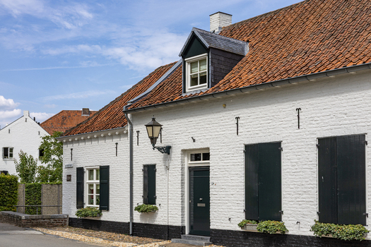 View of a traditional white painted brick house with black shutters and a red tiled roof in the historic town of Thorn Limburg Netherlands. View of a traditional white painted brick house with black shutters and a red tiled roof in the historic town of Thorn Limburg Netherlands.