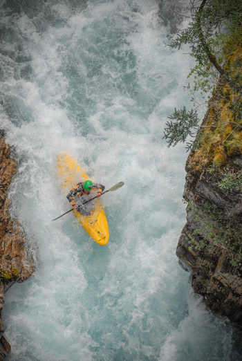 View of a kayaker in a yellow kayak navigating the white water rapids of the Rio Manso through a narrow rocky canyon in San Carlos de Bariloche Rio Negro Argentina. View of a kayaker in a yellow kayak navigating the white water rapids of the Rio Manso through a narrow rocky canyon in San Carlos de Bariloche Rio Negro Argentina.
