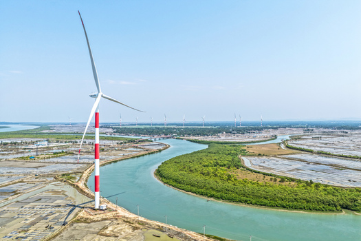 Aerial view of striking wind turbines standing tall against the turquoise river snaking through the landscape Cox s Bazar Chittagong Division Bangladesh. Aerial view of striking wind turbines standing tall against the turquoise river snaking through the landscape Cox s Bazar Chittagong Division Bangladesh.
