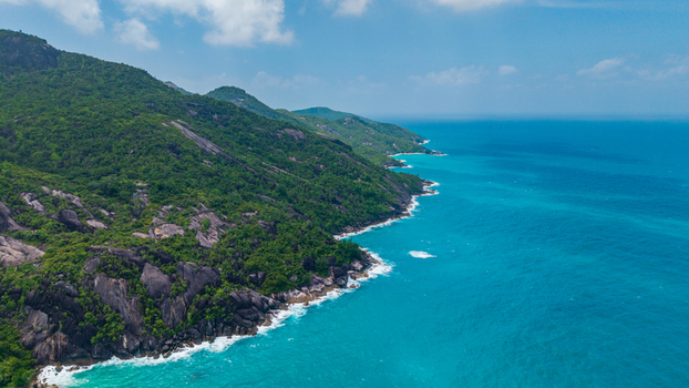 Aerial view of the lush green coastline and rocky cliffs near the Anse Soleil Beachcomber Hotel Mahe Baie Lazare Seychelles.