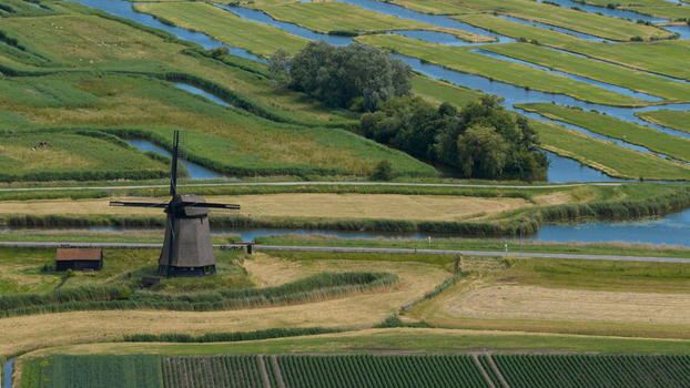 Aerial view of De Museummolen windmill surrounded by lush green polder fields winding canals and agricultural land in Schermerhorn Noord Holland Netherlands. Aerial view of De Museummolen windmill surrounded by lush green polder fields winding canals and agricultural land in Schermerhorn Noord Holland Netherlands.