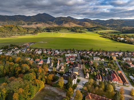 Aerial view of a picturesque village nestled against a rolling green expanse framed by majestic mountains and a dramatic cloudy sky Mosovce Zilina Region Slovakia. Aerial view of a picturesque village nestled against a rolling green expanse framed by majestic mountains and a dramatic cloudy sky Mosovce Zilina Region Slovakia.