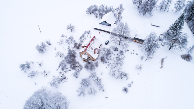 Aerial view of a house surrounded by snow covered trees and fields in a winter landscape Latvia. Aerial view of a house surrounded by snow covered trees and fields in a winter landscape Latvia.
