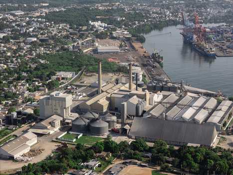 Aerial view of industrial port facilities with storage silos factory buildings and cargo ships docked at the harbor in Bajos de Haina San Cristobal Provinc Dominican Republic.