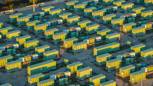 Aerial view of modular battery storage containers and electrical equipment at a modern energy facility illuminated by warm evening sunlight in Italy. Aerial view of modular battery storage containers and electrical equipment at a modern energy facility illuminated by warm evening sunlight in Italy.
