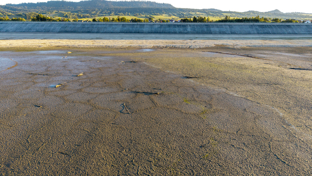 Aerial view of the dried up bed of Czorsztyn Reservoir with cracked mud patterns and a concrete dam embankment in the background in Czorsztyn Lesser Poland Voivode Poland. Aerial view of the dried up bed of Czorsztyn Reservoir with cracked mud patterns and a concrete dam embankment in the background in Czorsztyn Lesser Poland Voivode Poland.