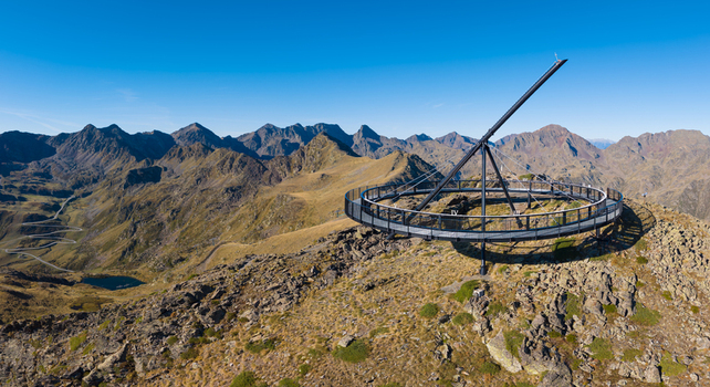 Aerial view of the Tristaina Sundial Balcony on a mountain peak surrounded by rugged Pyrenees mountains winding roads and a small alpine lake Ordino Ordino Andorra.