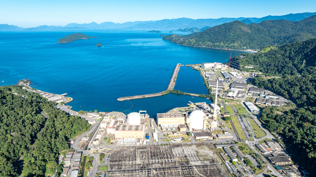Aerial view of the Angra 2 Nuclear Power Plant with containment domes and industrial facilities nestled between lush mountains and the blue sea in Angra dos Reis Rio de Janeiro Brazil.
