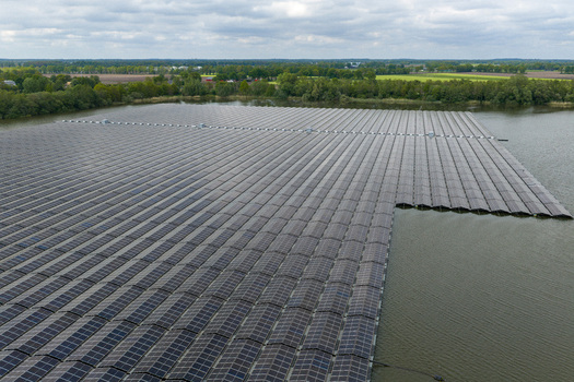 Aerial view of a massive floating solar farm on a lake surrounded by lush green forests and rural fields in Beilen Drenthe Netherlands. Aerial view of a massive floating solar farm on a lake surrounded by lush green forests and rural fields in Beilen Drenthe Netherlands.