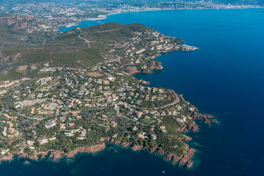 Aerial view of Le Trayas showing the red rock coastline Mediterranean Sea lush greenery and villas along the coastal roads in Saint Raphael Provence Alpes Cote d Azur France. Aerial view of Le Trayas showing the red rock coastline Mediterranean Sea lush greenery and villas along the coastal roads in Saint Raphael Provence Alpes Cote d Azur France.