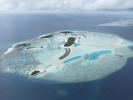 Aerial view of a tropical island resort featuring overwater bungalows lush vegetation and vibrant turquoise water surrounded by deep blue ocean Maldives. Aerial view of a tropical island resort featuring overwater bungalows lush vegetation and vibrant turquoise water surrounded by deep blue ocean Maldives.