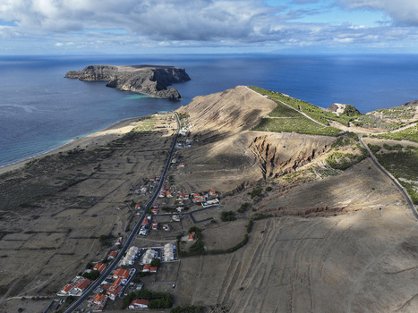 Aerial view of Ponta da Calheta featuring rugged coastal cliffs a sandy beach scattered houses and the Atlantic Ocean in Porto Santo Madeira Portugal. Aerial view of Ponta da Calheta featuring rugged coastal cliffs a sandy beach scattered houses and the Atlantic Ocean in Porto Santo Madeira Portugal.