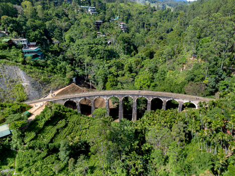 Aerial view of the historic Nine Arch Bridge surrounded by lush green tea plantations and dense forest in Demodara Uva Province Sri Lanka. Aerial view of the historic Nine Arch Bridge surrounded by lush green tea plantations and dense forest in Demodara Uva Province Sri Lanka.