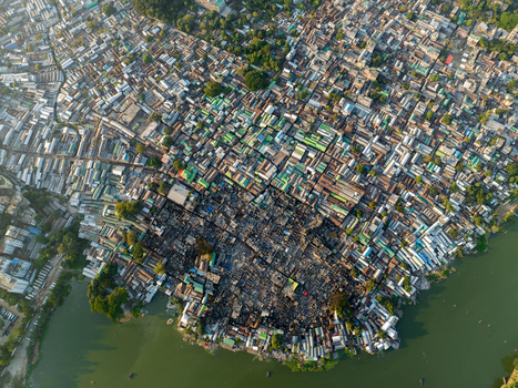 Aerial view of densely packed buildings and winding streets create a mosaic of textures contrasting sharply with the serene green river below Dhaka Dhaka Division Bangladesh. Aerial view of densely packed buildings and winding streets create a mosaic of textures contrasting sharply with the serene green river below Dhaka Dhaka Division Bangladesh.