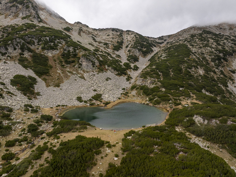 Aerial view of Muratovo Lake surrounded by rocky mountain slopes and alpine vegetation in Pirin National Park Blagoevgrad Province Bulgaria. Aerial view of Muratovo Lake surrounded by rocky mountain slopes and alpine vegetation in Pirin National Park Blagoevgrad Province Bulgaria.