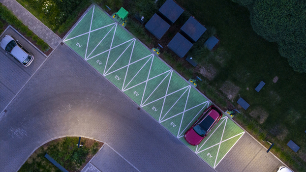 Aerial view of an electric vehicle charging station with green painted parking spaces and a red car parked in Poland. Aerial view of an electric vehicle charging station with green painted parking spaces and a red car parked in Poland.