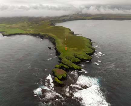 Aerial view of Tjornes peninsula with its grassy cliffs rocky coastline and a prominent communication tower surrounded by the North Atlantic Ocean in Tjorneshreppur Iceland. Aerial view of Tjornes peninsula with its grassy cliffs rocky coastline and a prominent communication tower surrounded by the North Atlantic Ocean in Tjorneshreppur Iceland.