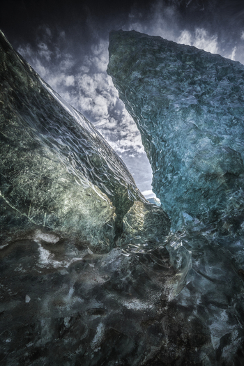 View of the translucent blue ice formations of the Vatnajokull glacier under a dramatic cloudy sky Iceland.
