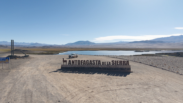Aerial view of the Antofagasta de la Sierra sign in a vast high altitude desert landscape with a lagoon and mountains Antofagasta de la Sierra Catamarca Province Argentina.