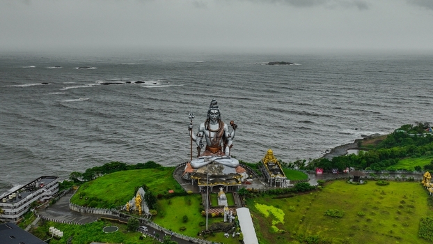 Aerial view of the giant Shiva statue at Murudeshwar Temple overlooking the Arabian Sea with lush green surroundings in Murdeshwar Karnataka India.