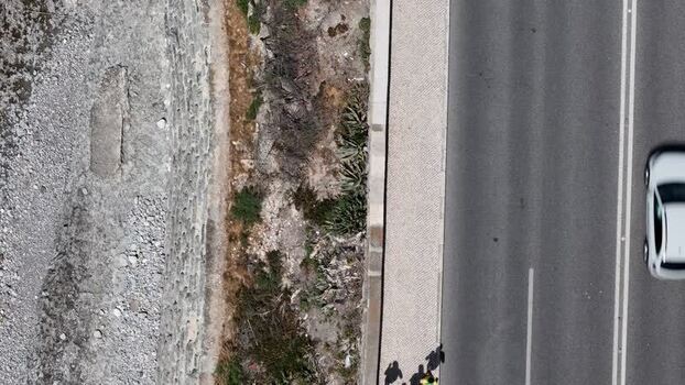 Aerial view of a white car driving on a road.