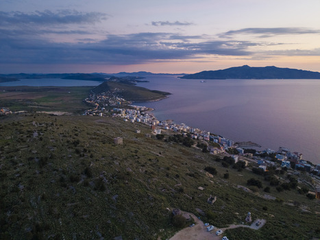 Aerial view of the coastal town of Saranda at sunset featuring buildings along the Ionian Sea rolling hills and a calm bay in Saranda Vlore County Albania. Aerial view of the coastal town of Saranda at sunset featuring buildings along the Ionian Sea rolling hills and a calm bay in Saranda Vlore County Albania.