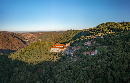 Aerial view of the Monastery of Santo Estevo de Ribas de Sil nestled in lush green hills of the Ribeira Sacra region with stone buildings and surrounding forests. O Covelo Ourense Spain.