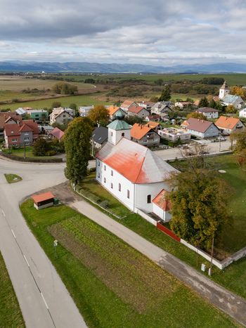 Aerial view of the prominent white church with a vibrant red roof amidst green fields and a charming village Haj Zilina Region Slovakia. Aerial view of the prominent white church with a vibrant red roof amidst green fields and a charming village Haj Zilina Region Slovakia.