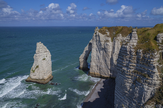 Aerial view of the needle like rock formations and the dramatic arch of &Eacute;tretat cliffs contrast with the turquoise sea &Eacute;tretat Normandy France.