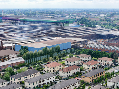 Aerial view of the large industrial complex and residential houses surrounded by green trees and flat landscape Dalmine Lombardy Italy. Aerial view of the large industrial complex and residential houses surrounded by green trees and flat landscape Dalmine Lombardy Italy.