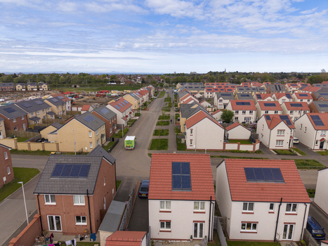 Aerial view of a modern residential neighborhood featuring houses with solar panels on rooftops and a delivery van on the street in Edinburgh Scotland United Kingdom.