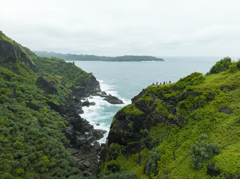 Aerial view of the cliffs meeting the turquoise ocean a group of people standing overlooking the landscape from Pengilon Hill Gunungkidul Regency Indonesia. Aerial view of the cliffs meeting the turquoise ocean a group of people standing overlooking the landscape from Pengilon Hill Gunungkidul Regency Indonesia.