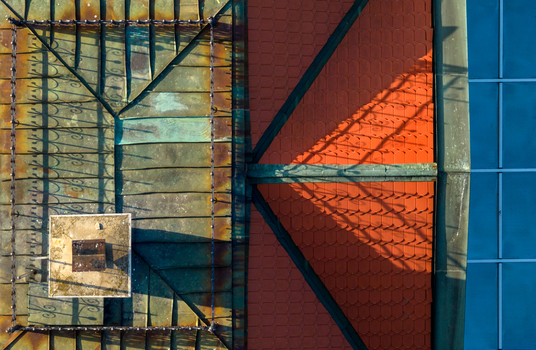 Aerial view of a roof featuring weathered copper sheeting and vibrant red tiles with a chimney and intricate shadows cast across the surface in Belgrade City of Belgrade Serbia. Aerial view of a roof featuring weathered copper sheeting and vibrant red tiles with a chimney and intricate shadows cast across the surface in Belgrade City of Belgrade Serbia.