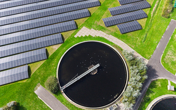 Aerial view of a solar farm with rows of photovoltaic panels surrounding a circular water treatment tank in Schagerbrug Noord Holland Netherlands. Aerial view of a solar farm with rows of photovoltaic panels surrounding a circular water treatment tank in Schagerbrug Noord Holland Netherlands.
