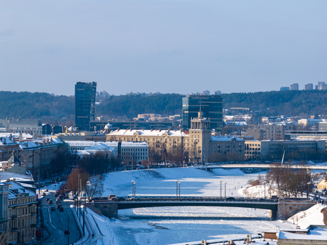 Aerial view of the frozen Neris River city bridges and urban skyline under a clear winter sky in Vilnius County Lithuania.