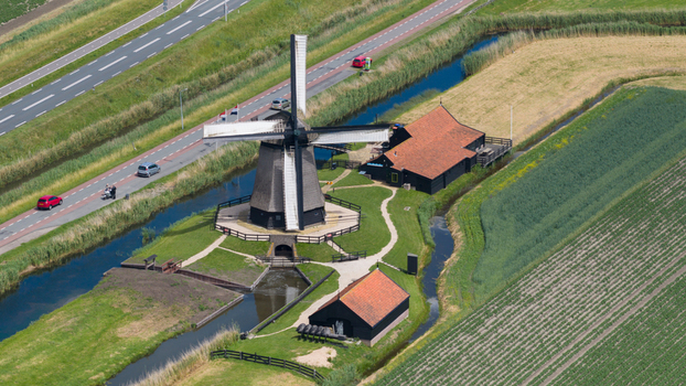 Aerial view of De Museummolen a historic windmill surrounded by green fields canals and a road in the Dutch countryside Schermerhorn Noord Holland Netherlands. Aerial view of De Museummolen a historic windmill surrounded by green fields canals and a road in the Dutch countryside Schermerhorn Noord Holland Netherlands.